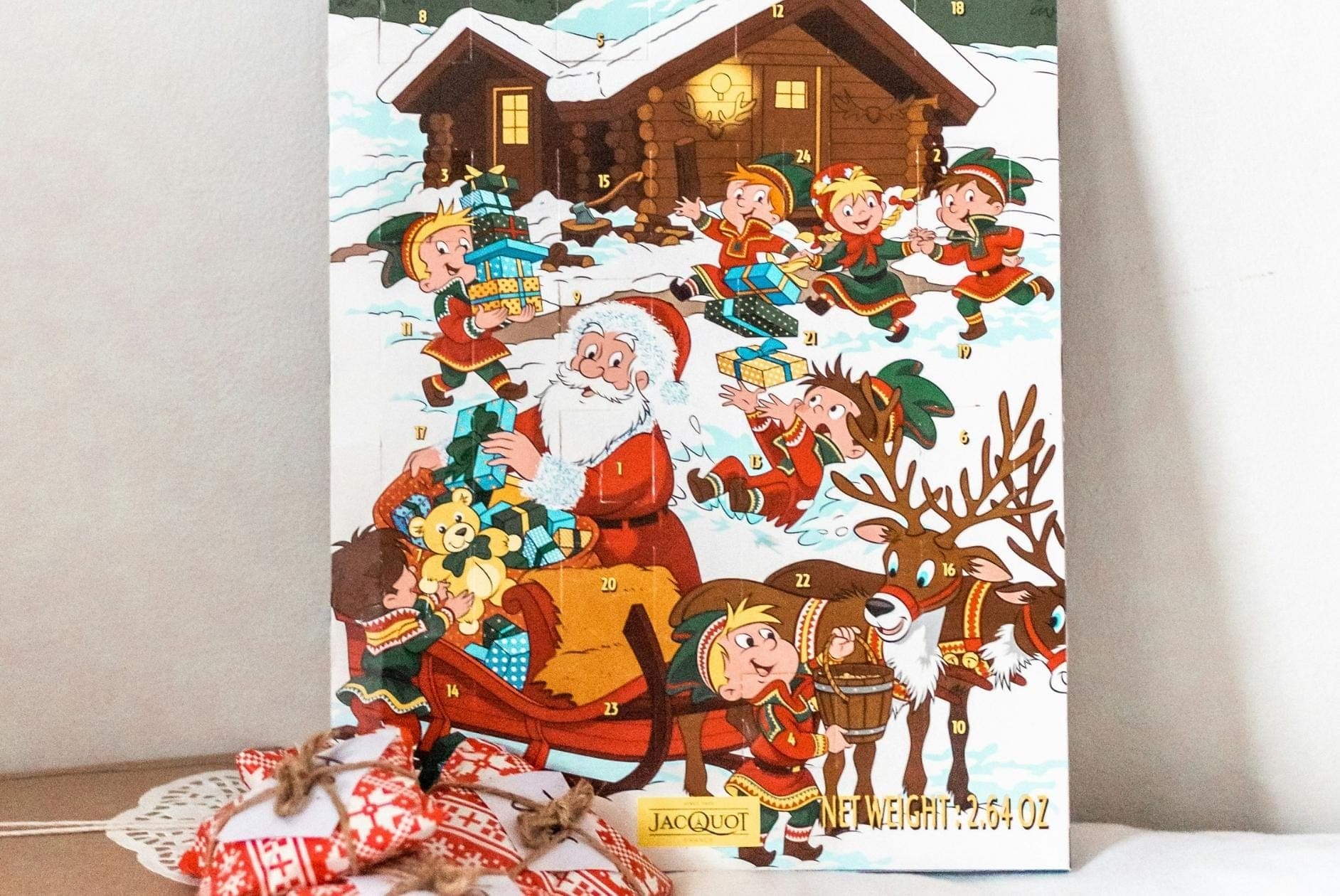 Headerbild mit Adventskalender mit Weihnachtsmann, Rentieren und Elfen vor einer Wand