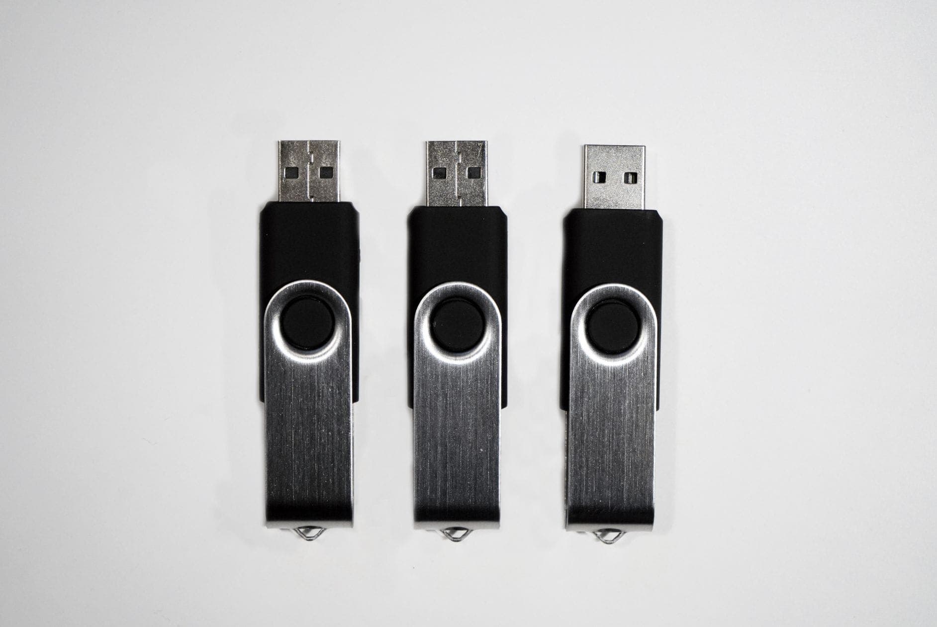 Headerbild mit drei USB-Sticks nebeneinander auf grauem Hintergrund.
