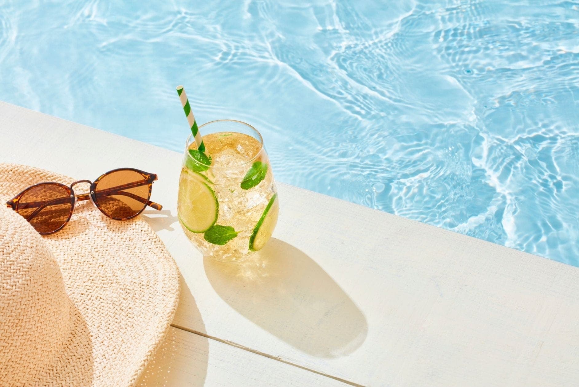 Header: Pool mit Glas Limonade, Hut und Sonnenbrille