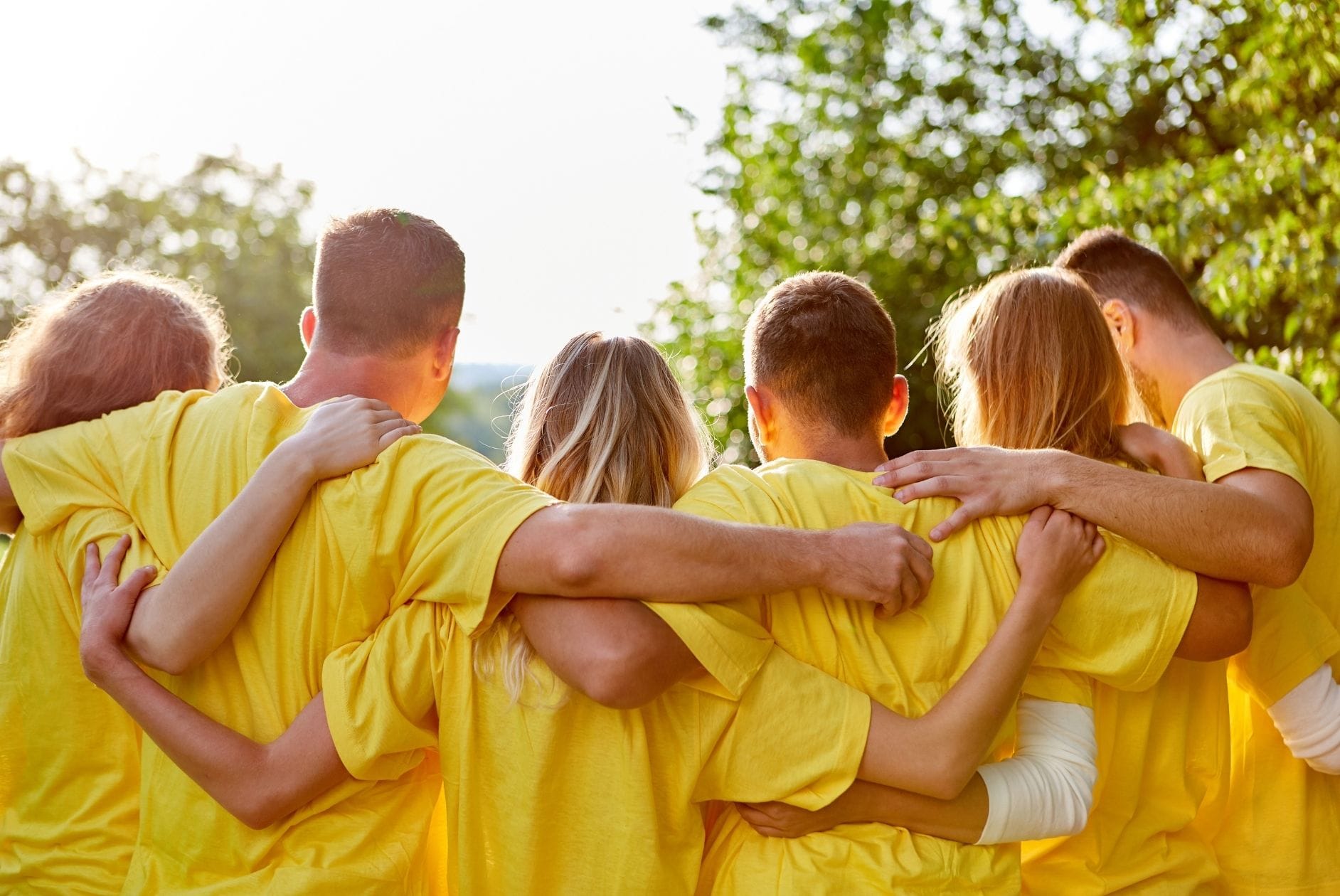 Header: Personen umarmen sich und tragen gelbe Shirts als Teamwear